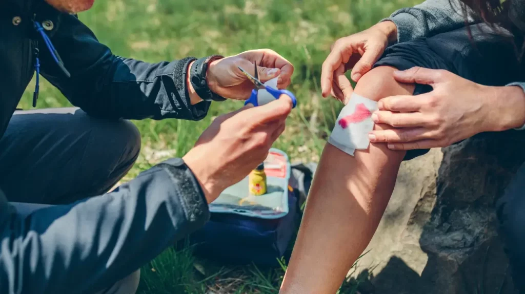 man-healing-knee-to-woman-who-has-been-injured-first-aid-kit
